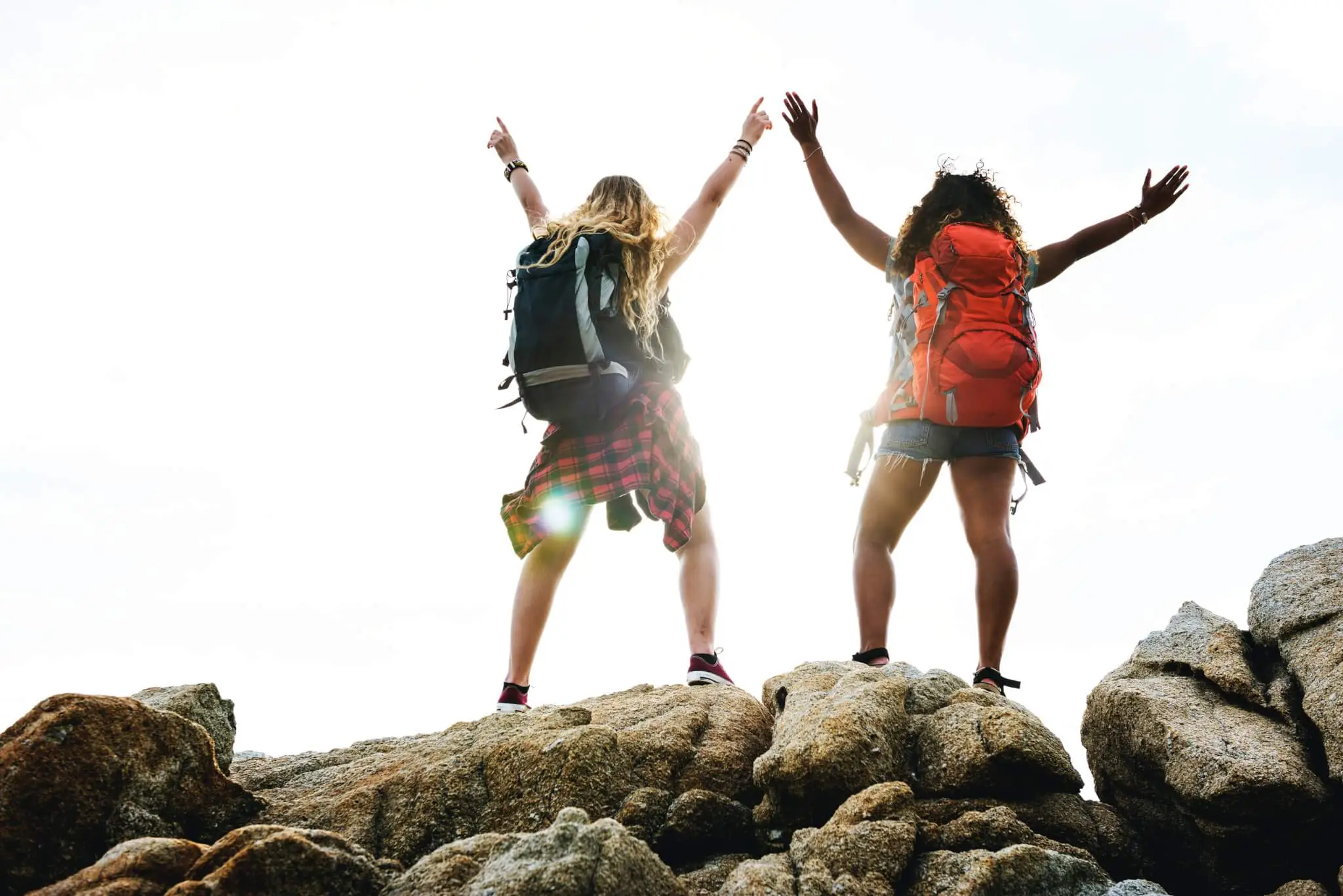 Two women on a hill with travel backpacks on.