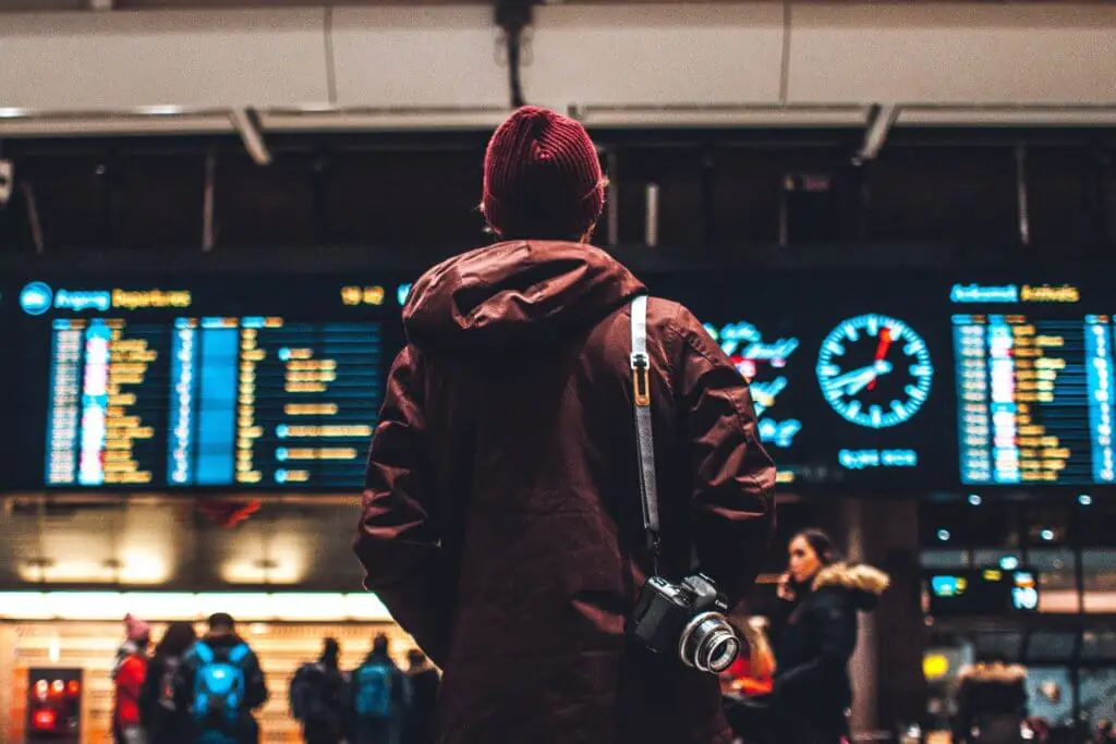 Man standing in front of a schedule board at the airport