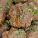 Italian meatballs piled in a serving dish garnished with parsley.