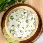 An overhead shot of cilantro lime rice surrounded by limes and cilantro.