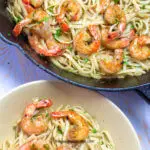 A bowl of shrimp scampi next to a pan full of more scampi.