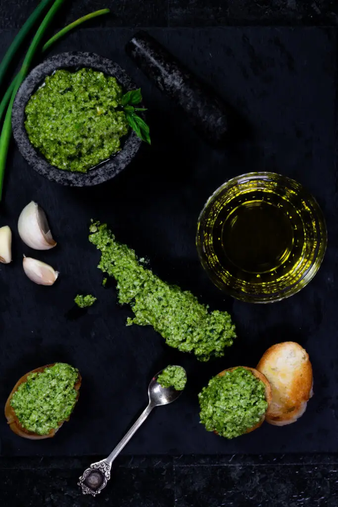 A flatlay of garlic scape pesto on a slate serving board