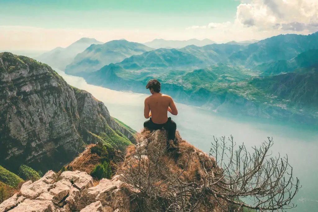 A man sitting on a cliff in Italy.