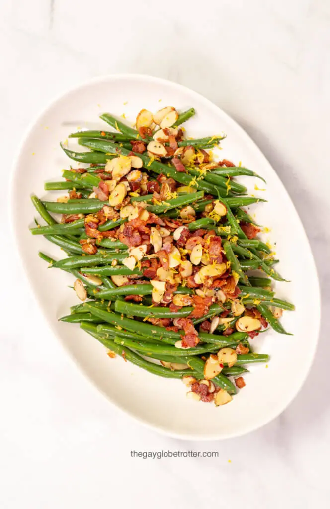 A serving platter with green beans almondine with bacon.