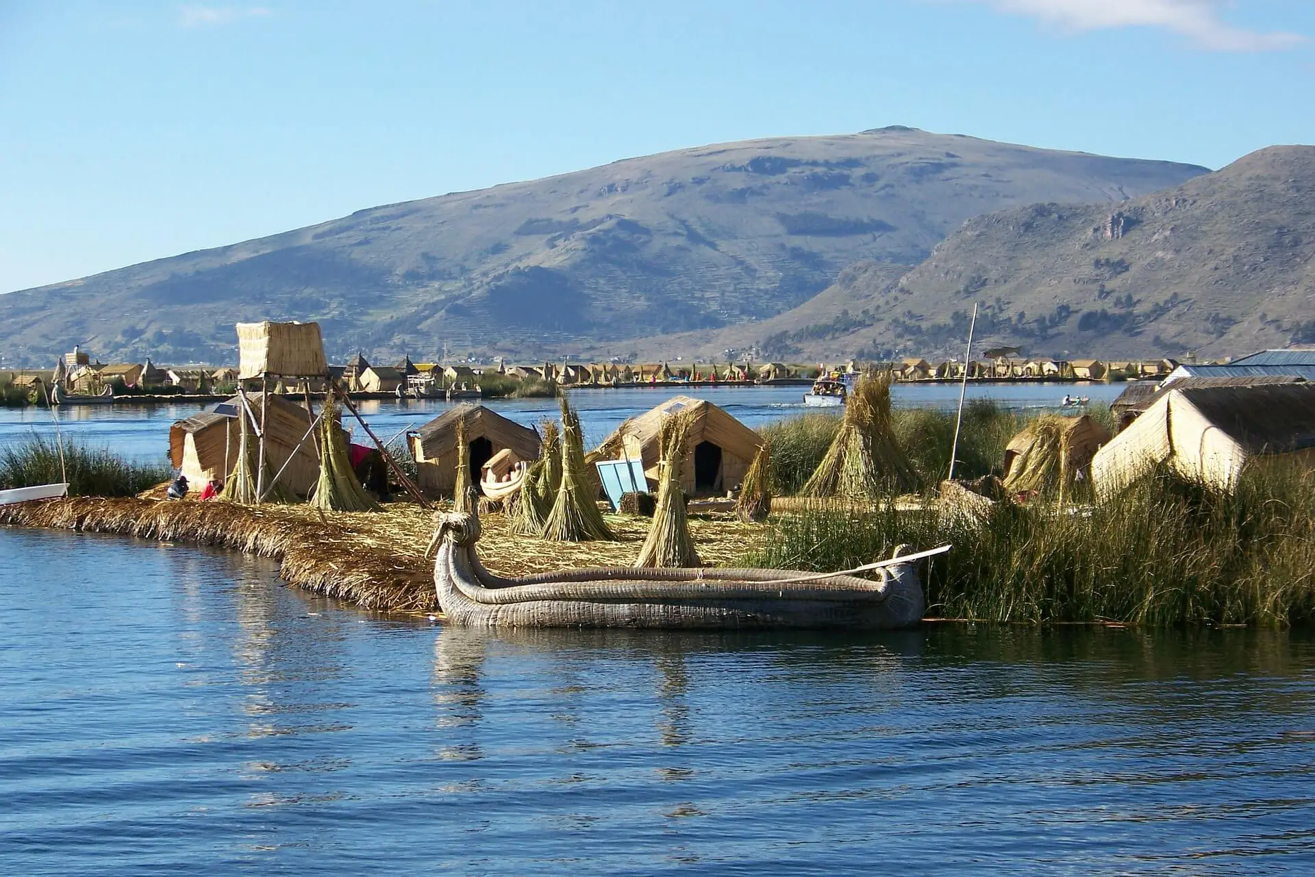 A boat floating on Lake Titicaca in Peru near hay huts