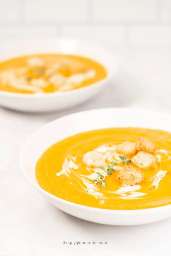 A bowl of creamy carrot soup being served.