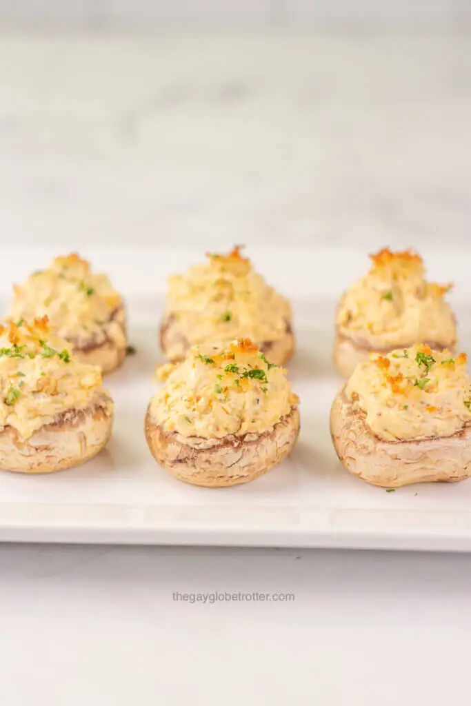 A plate full of stuffed mushrooms with breadcrumb topping.