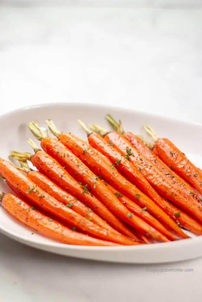 Honey glazed carrots garnished with parsley in a serving dish.