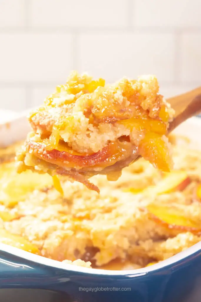 A wooden serving spoon with a scoop of peach cobbler.