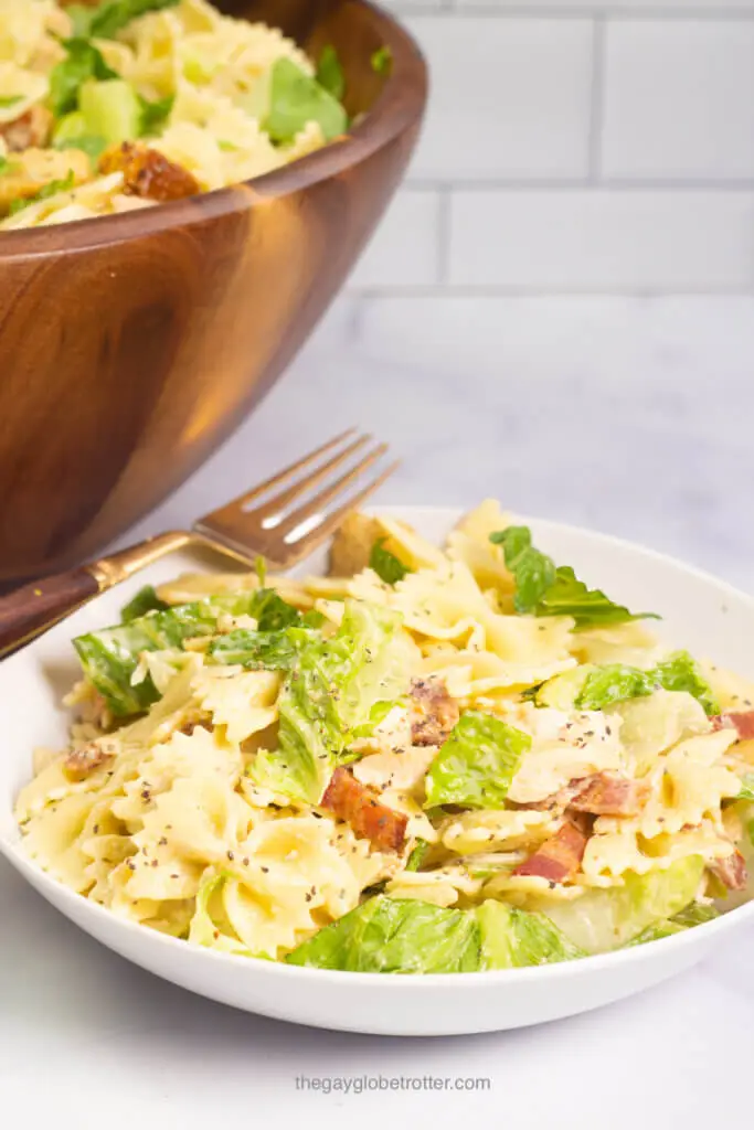 A white bowl full of chicken caesar pasta salad with a fork. 