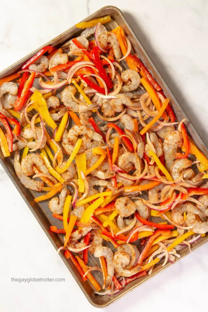 Shrimp, peppers, and onions on a baking sheet.