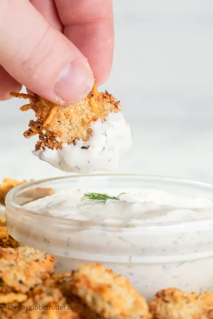 An air fryer pickle being dipped into fresh dill dip.