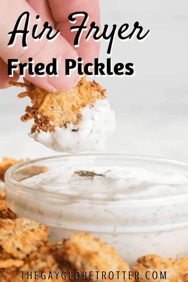 An air fried pickle being dipped in dill dip.