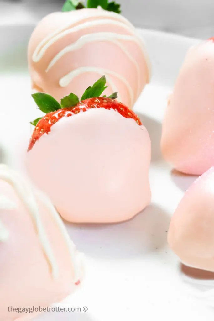 Pink chocolate covered strawberries on a serving plate.