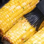 Butter bing brushed on corn in the air fryer.