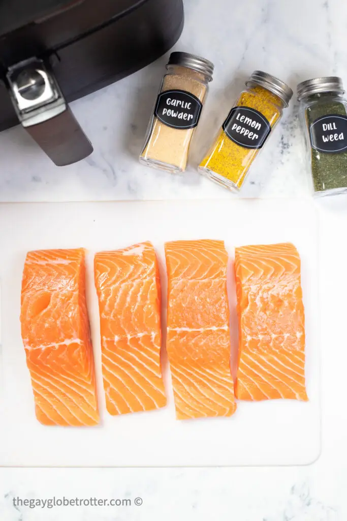 Raw salmon next to spices and an air fryer.