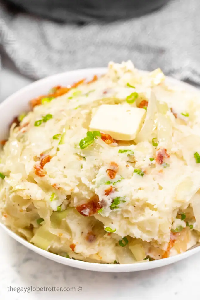 Colcannon in a serving dish topped with butter.