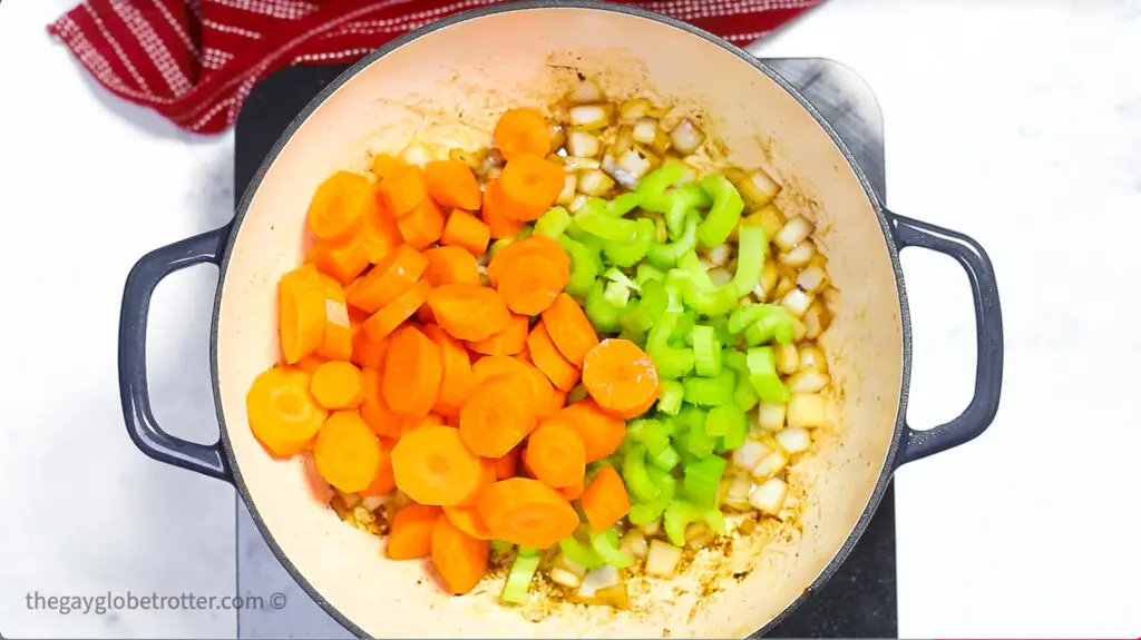 Celery, carrots, and onions in a pot.