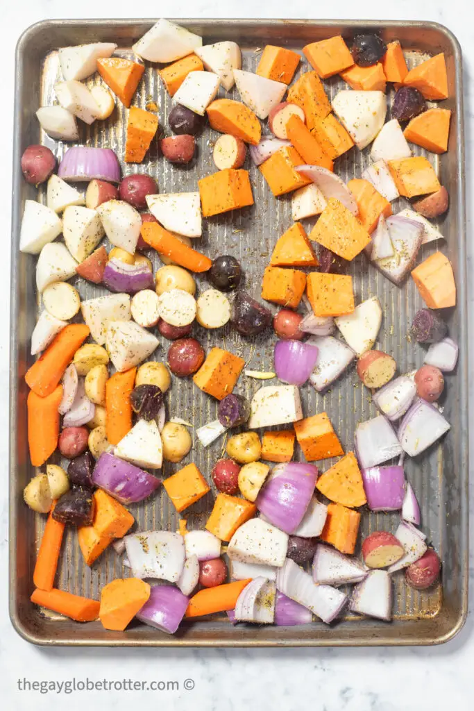 Raw root vegetables on a baking sheet ready to roast.