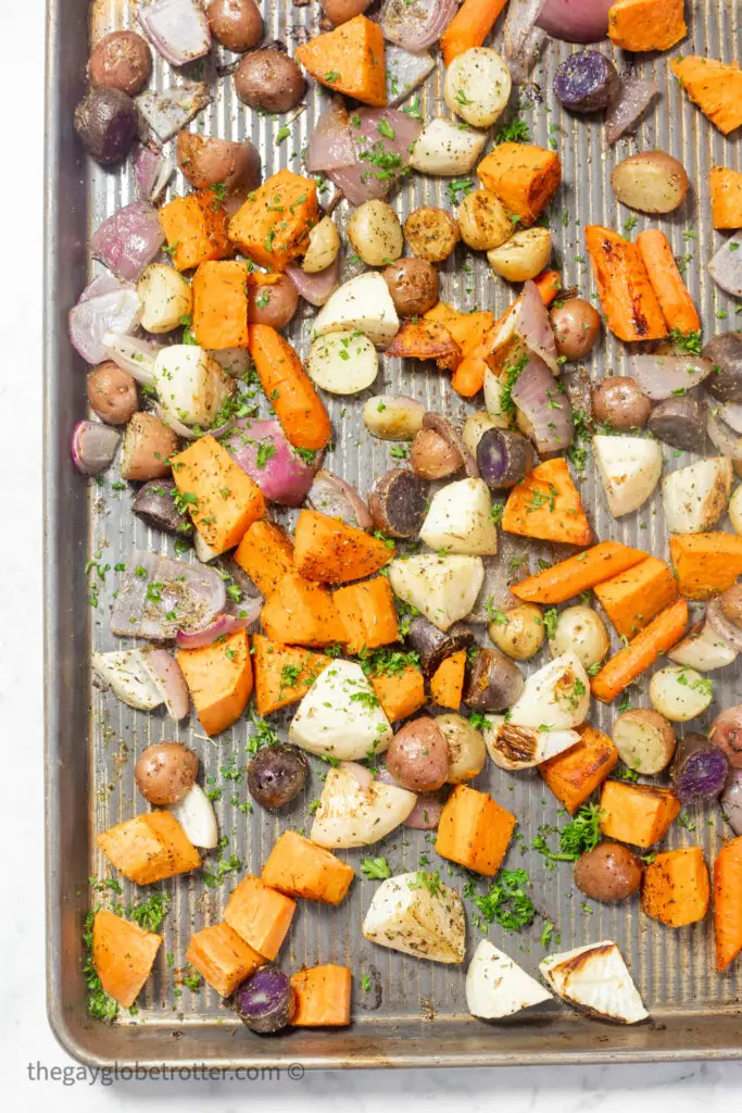 Roasted root vegetables garnished with parsley on a baking sheet.