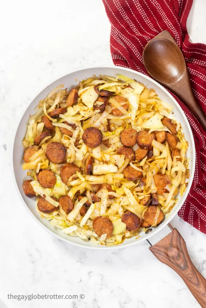 Cabbage and sausage being fried.