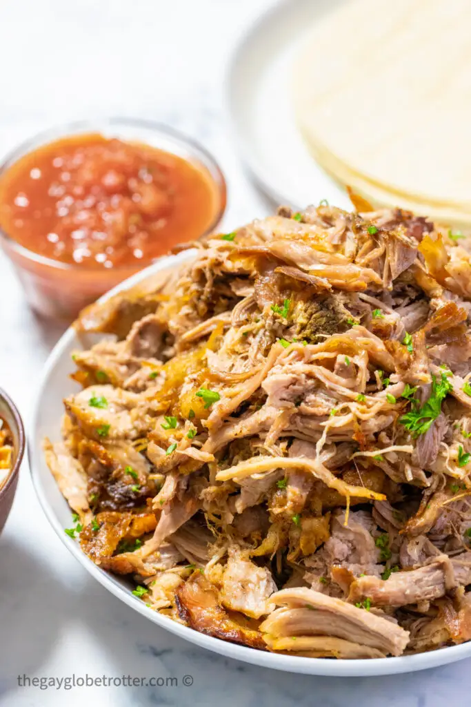 A serving platter of slow cooker pork carnitas with parsley.