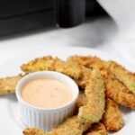 Air fryer avocado fries next to sriracha ranch dipping sauce.