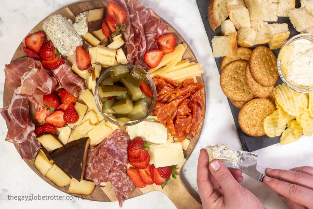 A hand spreading soft cheese on crostini.