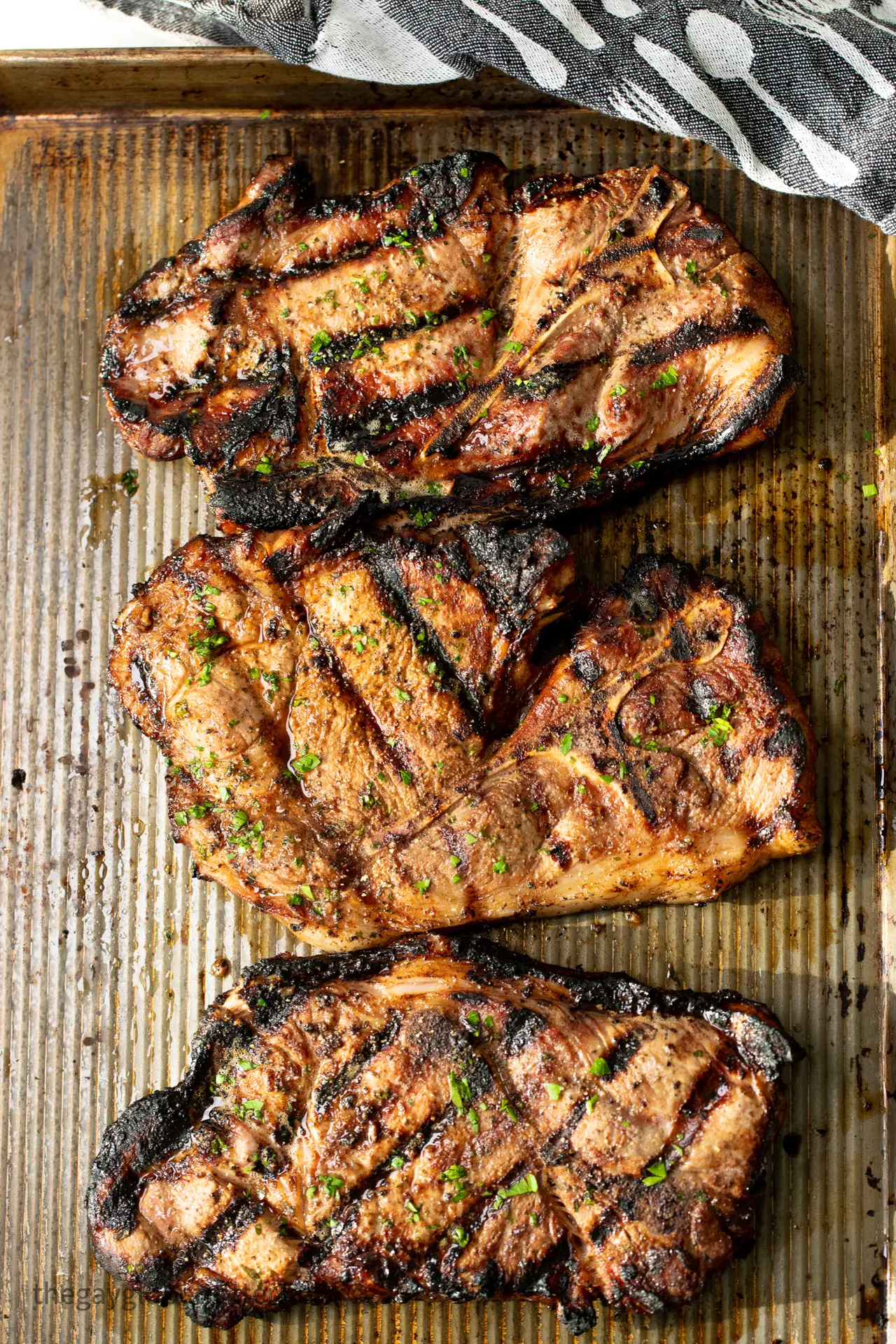 3 pork shoulder steaks on a baking sheet resting.