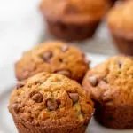 Three banana chocolate chip muffins on a plate.