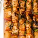 Skewers of hawaiian chicken and vegetables on a serving plate.