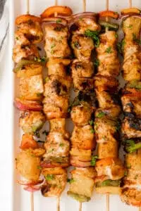 Skewers of hawaiian chicken and vegetables on a serving plate.